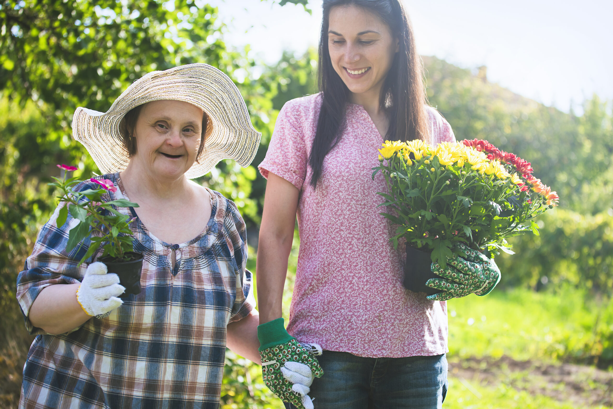 Person with intellectual or Developmental disability holding flowers in one hand and holding the hand of their caregiver with other hand