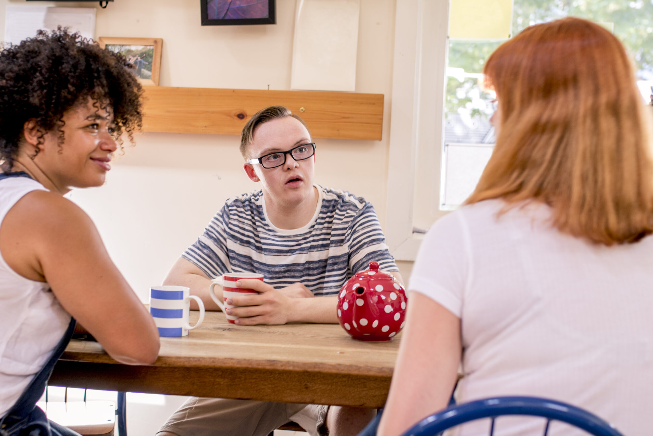 Two caregivers sitting at a table having a discussion with an adult living with an intellectual or developmental disability
